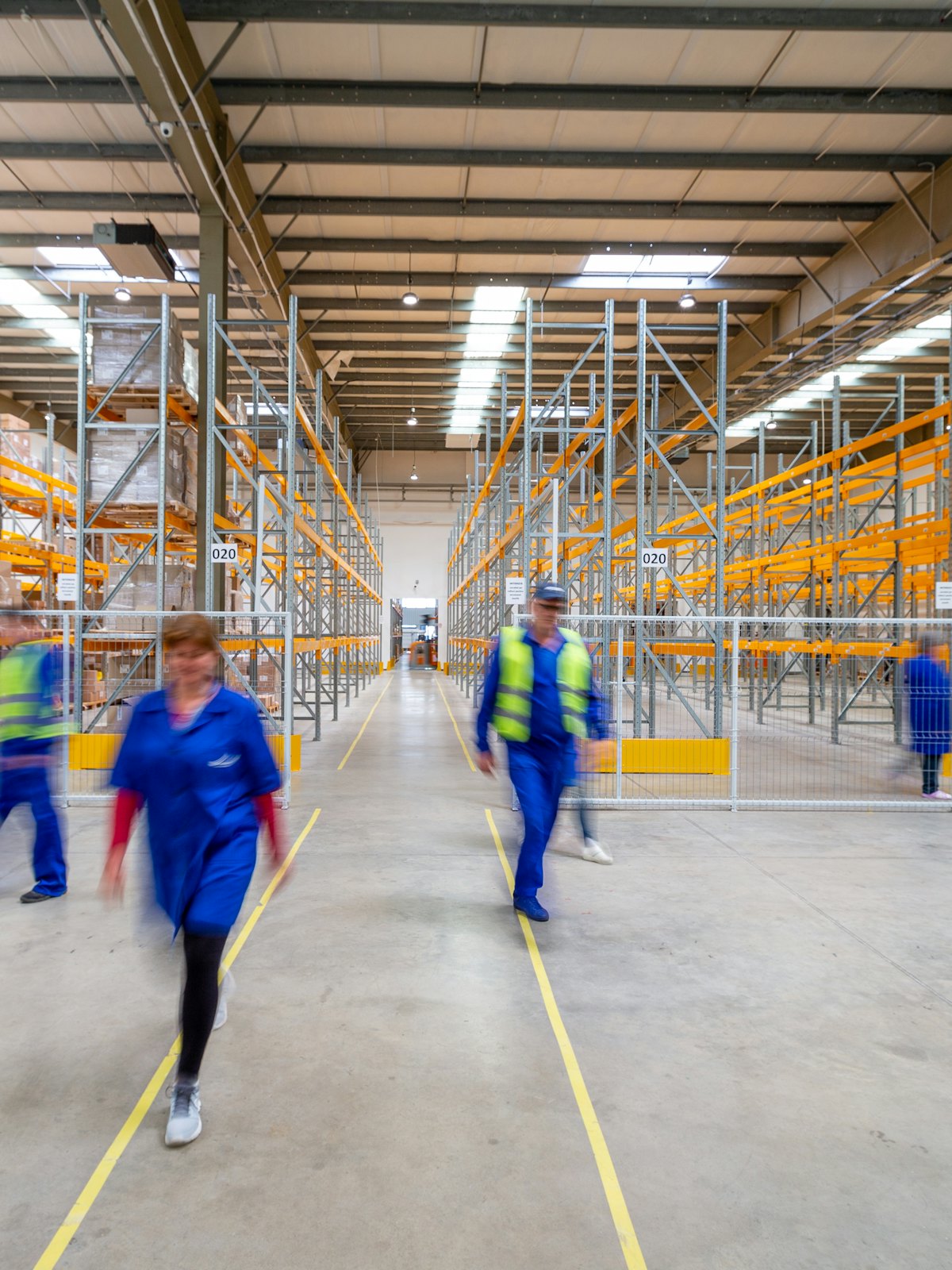 Warehouse team walking a lit aisle, the racking blurred by movement