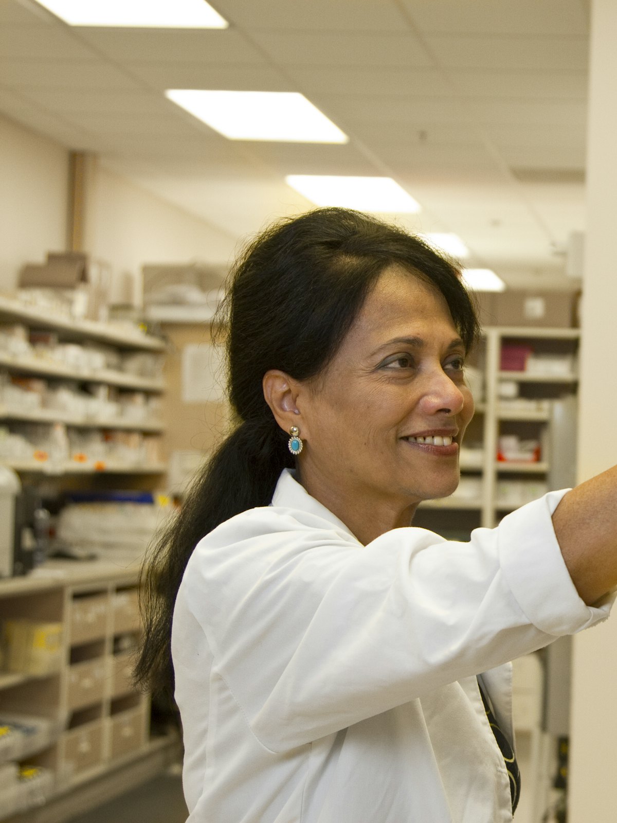 A pharmacist reaching for stock on a dispensary shelf