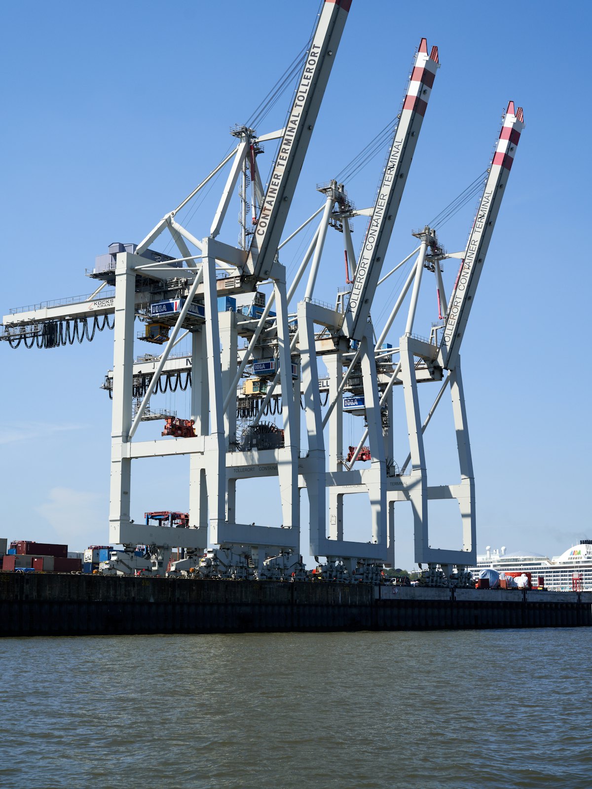 Quay cranes standing over a container berth against open sky