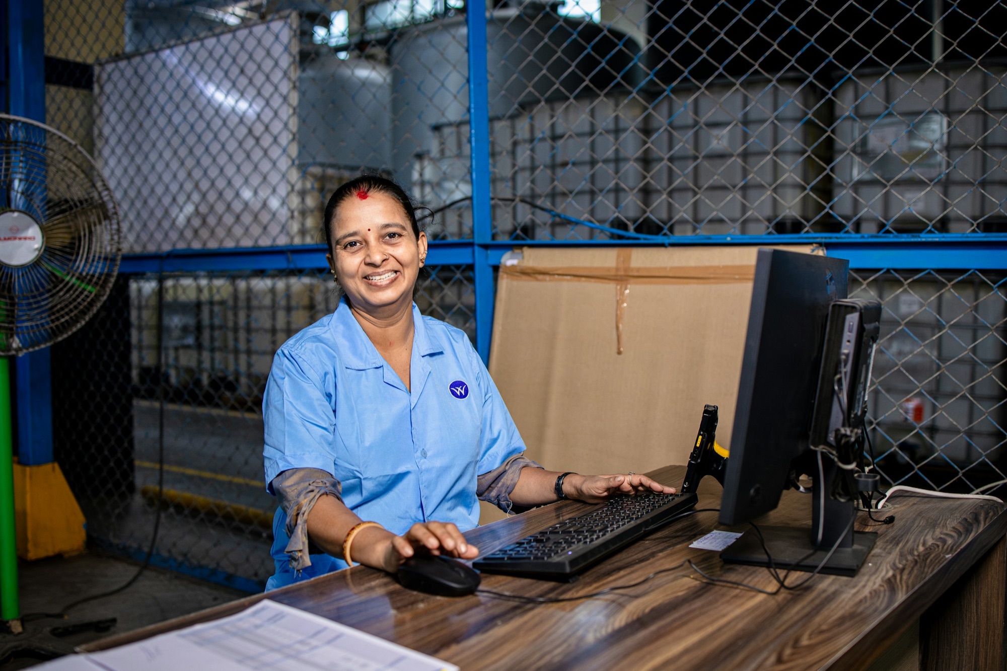 An order-desk operator smiling at her workstation in a warehouse office