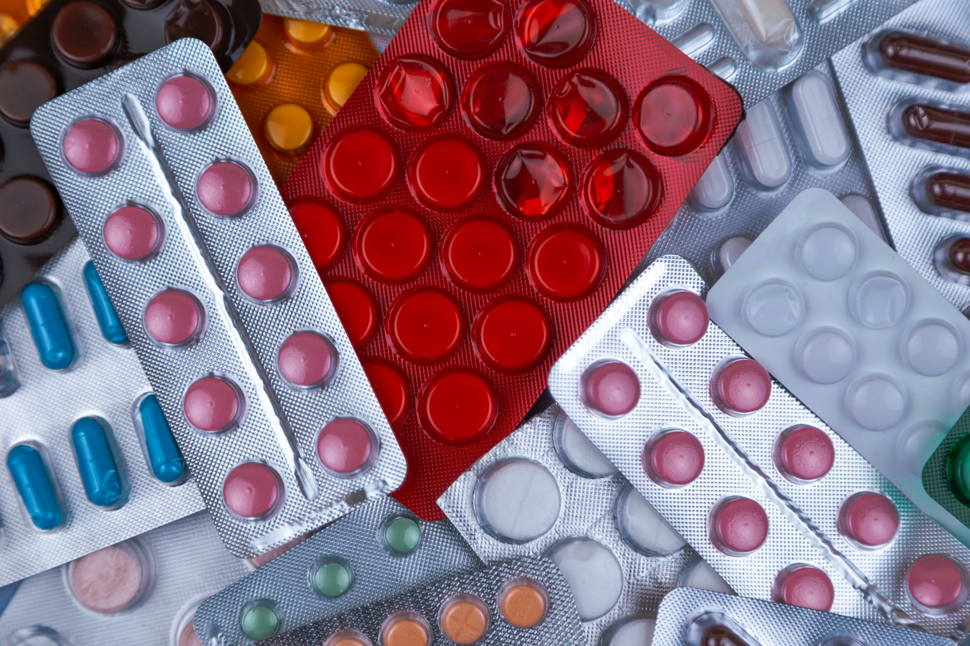 A heap of blister packs of tablets in red, white and blue