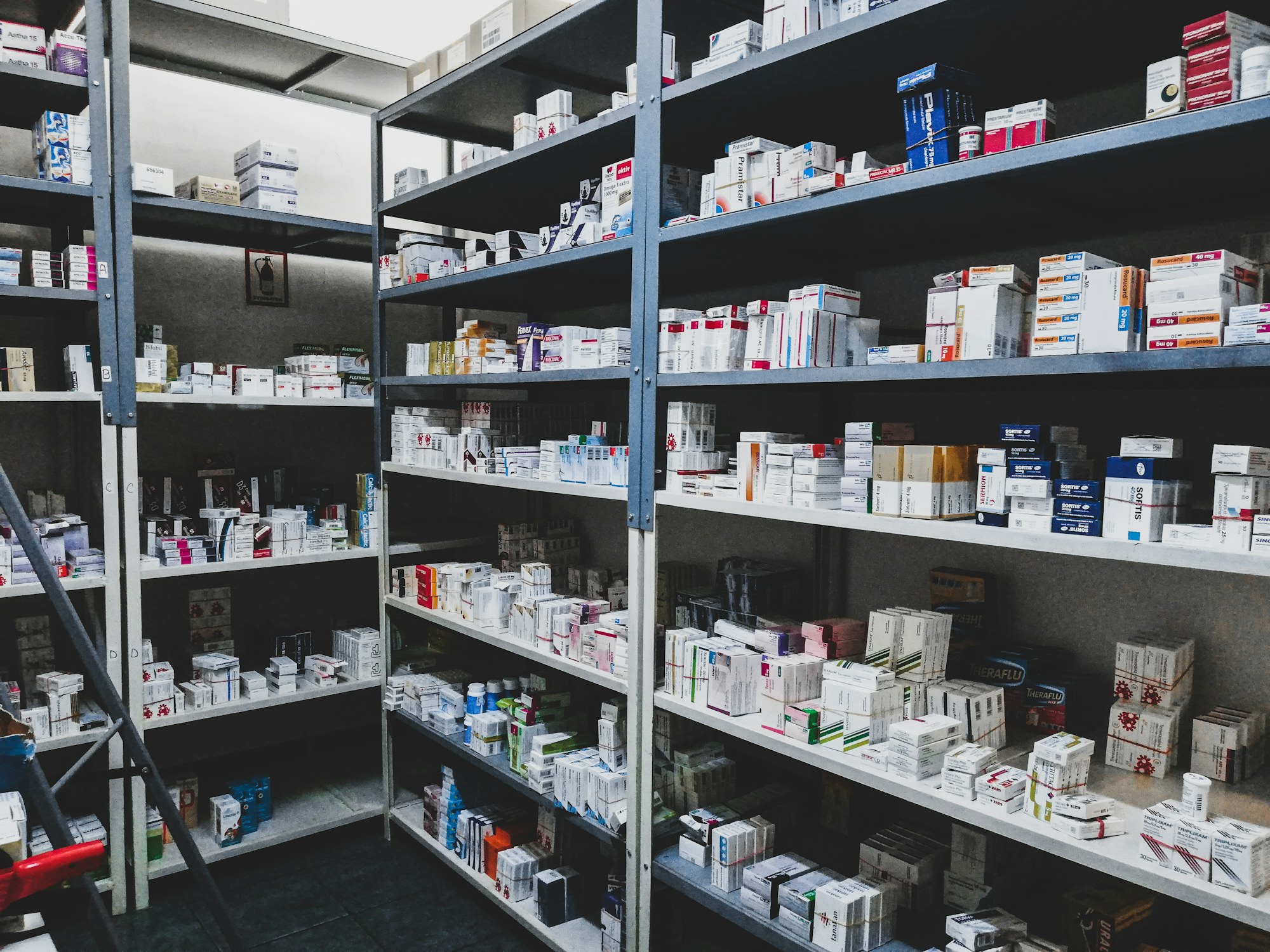 Pharmacy stockroom shelves packed with boxes of medicine